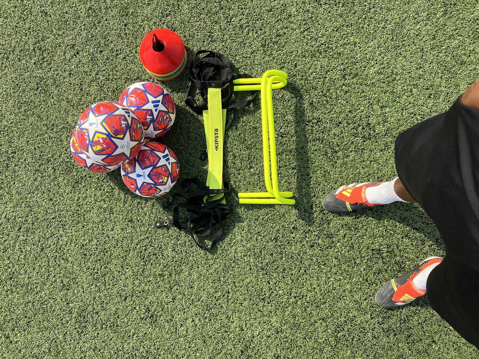 Sports academy equipment laid out on a pitch in Dubai including footballs cones and agility hurdles